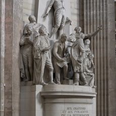 Commande publique 1903.L'obélisque adossé au pilier porte, en haut, la figure de la Victoire tenant une torche; en dessous, les grandes armes de France, surmontées de la couronne royale.