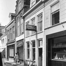 Huis met door toppilaster op kraagsteen bekroonde trapgevel en jongere winkelpui