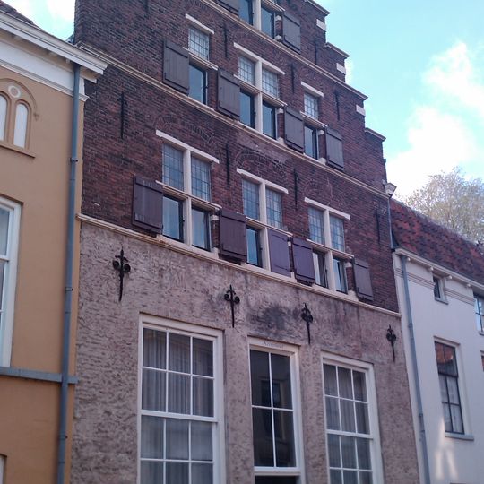 Onderkelderd pand met hoge trapgevel bekroond door topmakelaar op gebeeldhouwde kraagsteen