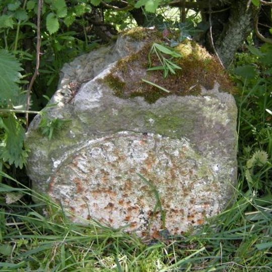 Milestone, northern end of village, just E of 90 degree bend, by entrance to some farm buildings
