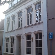 Pand met een op de omstreeks 1860-1870 gebruikelijke wijze gepleisterde lijstgevel van vijf traveeën met middenrisaliet en zijlisenen