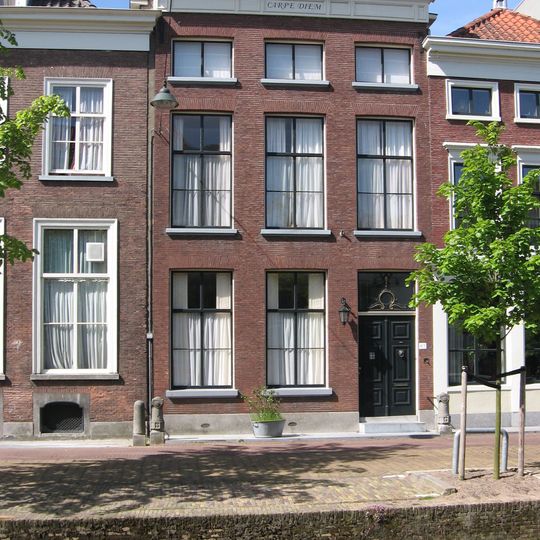 Pand achter eenvoudige, uit mooi metselwerk opgetrokken lijstgevel. Late Empireramen; in de lijst verdiepte velden. Stoephek met gebeeldhouwde palen