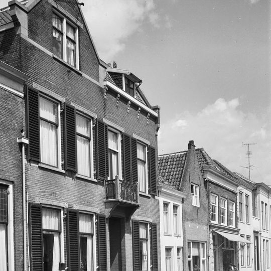 Pand met verdieping en hoog schilddak. Lijstgevel, eerste helft 19e eeuw, met in de verdieping negenruitsschuiframen