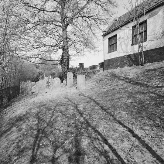 Begraafplaats omgeven door een haag van laurier, gelegen op een langgerekt perceel op de dijk van een wiel buiten de bebouwde kom van Leerdam, oostelijk van Oosterwijk