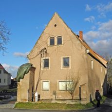 Wohnstallhaus (mit zwei Hausnummern) eines ehemaligen Dreiseithofes, dazu Hofmauer mit Torbogen Dorfplatz 13; 13a