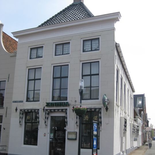 Diep hoekpand met gepleisterde voorgevel met rechte kroonlijst onder schilddak met twee topschoorstenen