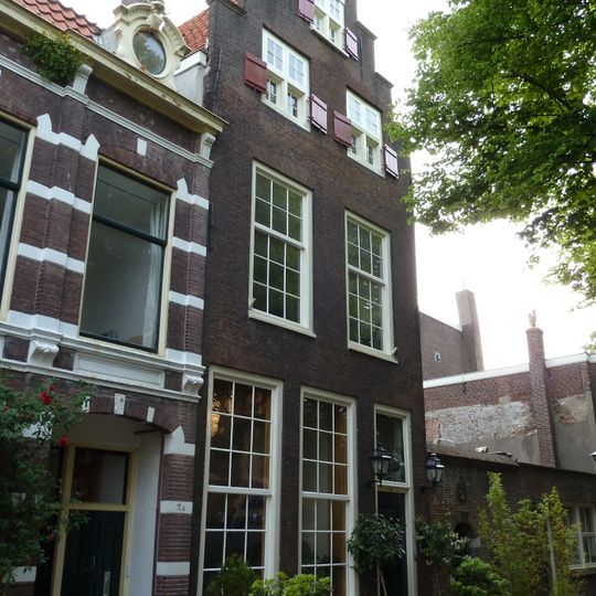 Pand met trapgevel met drie kruiskozijnen, in de top afgedekt met zandstenen tympaan