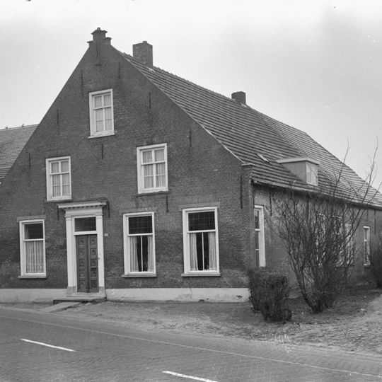 Boerderij van het Langstraatse type, met aan de voorzijde een door trappen en een toppilaster bekroonde tuitgevel; in de verdieping zesdelige schuiframen.