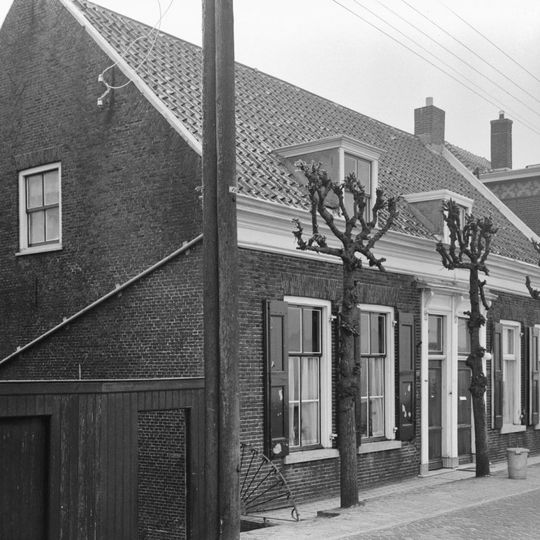 Dwarshuis van begane-grond met hoog schilddak. Deuromlijsting met hoofdgestel op gesneden consoles. Vensters met luiken en zesruitsschuiframen. Vormt een geheel met het buurnummer 277