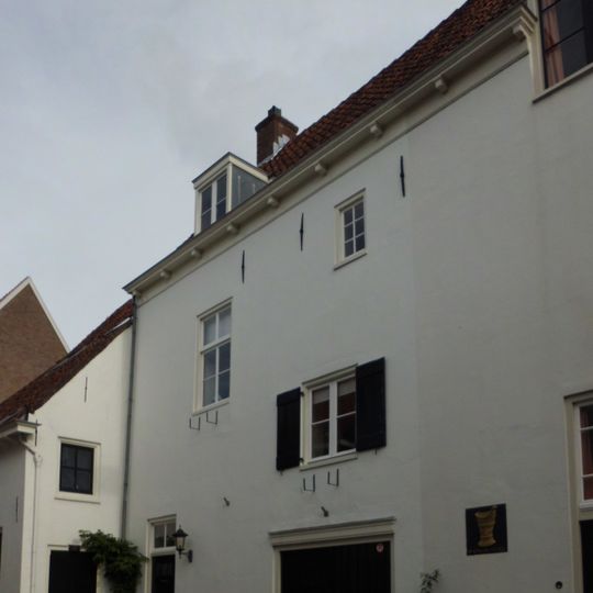 Gepleisterd pakhuis. In de gevel twee hijsbalken