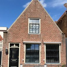 Laag pandje onder zadeldak tegen gepleisterde topgevel