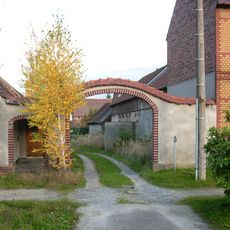 Hofmauer eines Bauernhofes mit großem Torbogen und kleiner Pforte Dorfstraße 66