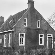 Woning met vier- en vijf en zesruitsvensters en twee kleine lichtopeningen onder dwars zadeldak tussen topgevels