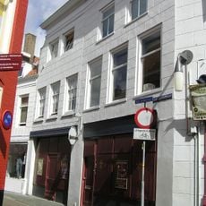 Huis met gepleisterde lijstgevel. Lijst gecombineerd met die van nr 52. Winkelpui