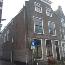 Pand met afgewolfde klokgevel door rechte kroonlijst halverwege afgedekt