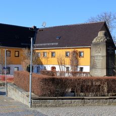 Wohnhaus über winkligem Grundriss, rückwärtige Scheune und Einfriedung Am Dorfplatz 14