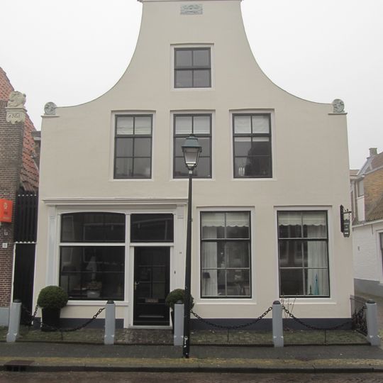 Pand met gepleisterde klokgevel met aanzetkrullen en driehoekig fronton