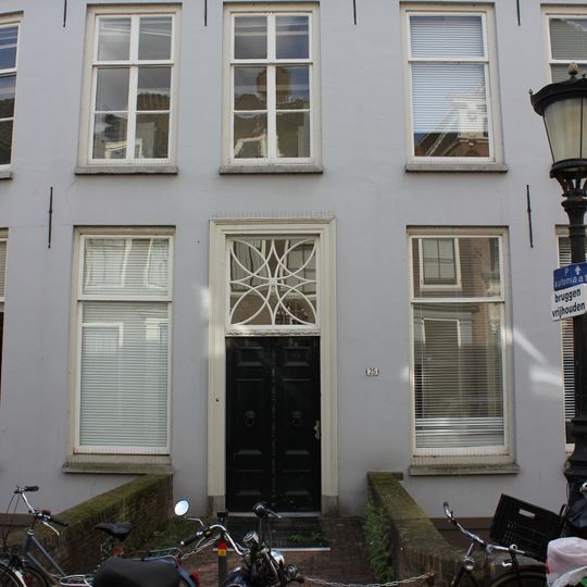 Huis in de bocht van de kromme nieuwegracht gelegen, langgerekte gepleisterde gevel met rechte kroonlijst, door zadeldak gedekt