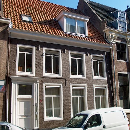 Gevel met omlijste ingang voor ouder pand met dwarskap tussen topgevels