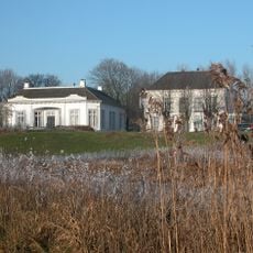 Gepleisterd rechthoekig gebouw onder schilddak met verdieping en houten veranda