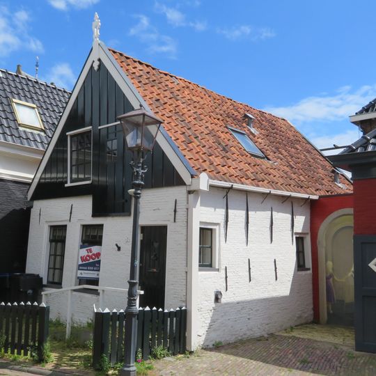 Gepleisterd huisje met puntgevel met houten voorschot en versierde topmakelaar