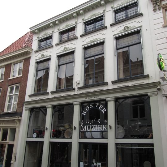 Huis met witgepleisterde en van stucversiering voorziene lijstgevel