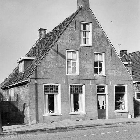 Pand tussen topgevels met zesruitsvensters in de top onder zadeldak met topschoorstenen