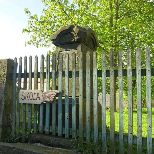 Kříž s ulomeným kovovým křížkem na zahradě domu na návsi v Zubrnicích