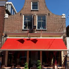 Pand onder zadeldak tegen klokgevel met aanzetkrullen en gezwenkte bekroning