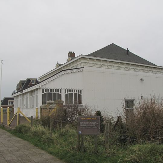 Houten saunagebouwtje op rechthoekige plattegrond, één bouwlaag hoog met aan één zijde afgewolfd zadeldak, gedekt met tuile du nord pannen