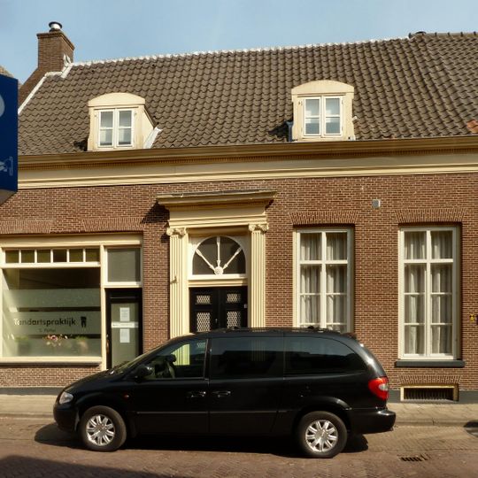 Linker gedeelte van een woonhuis van begane-grond met hoog, dwars zadeldak tussen puntgevels