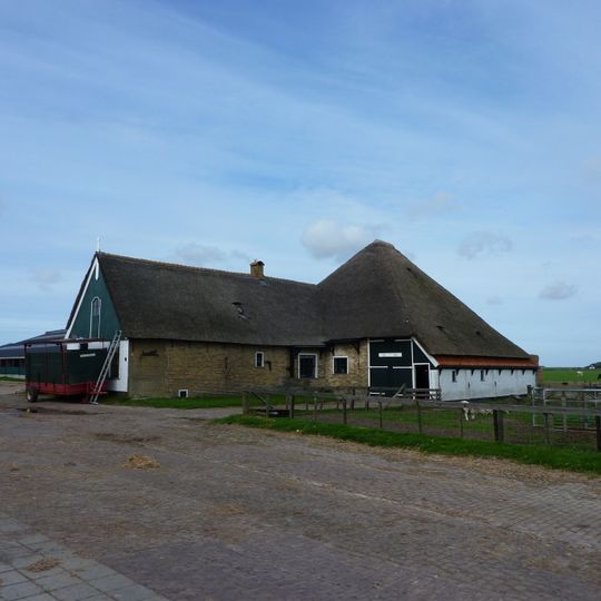 Zeer goed bewaarde gave stolp met groot uitgebouwd woonhuis; houten top met luik en versierde makelaar. In twee vertrekken lambrisering van witte tegels met blauwe rand