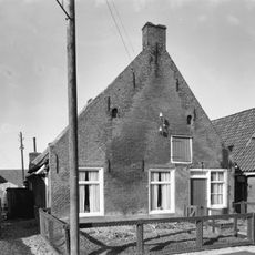 Pand onder zadeldak tegen topgevel met kleine openingen in de top