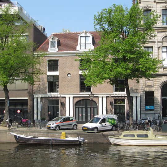 Breed koetshuis met gevel voorzien van gebosseerde hoeklisenen en rechte lijst waarop drie dakkapellen