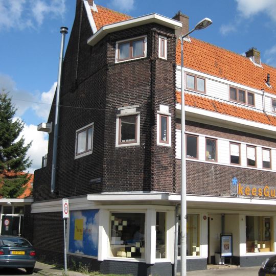Blok met winkels met brede luifel en daarboven woningen, bouwstijl Amsterdamse School, onderdeel van het centrale achthoekige plein van Tuindorp Nieuwendam