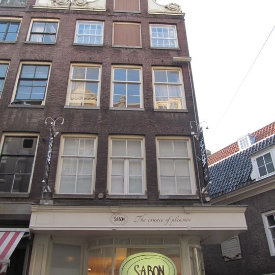 Hoekhuis met halsgevel met gedeelde vleugelstukken en schelp in de afdekking. Vormt groep met nrs 96 en 98