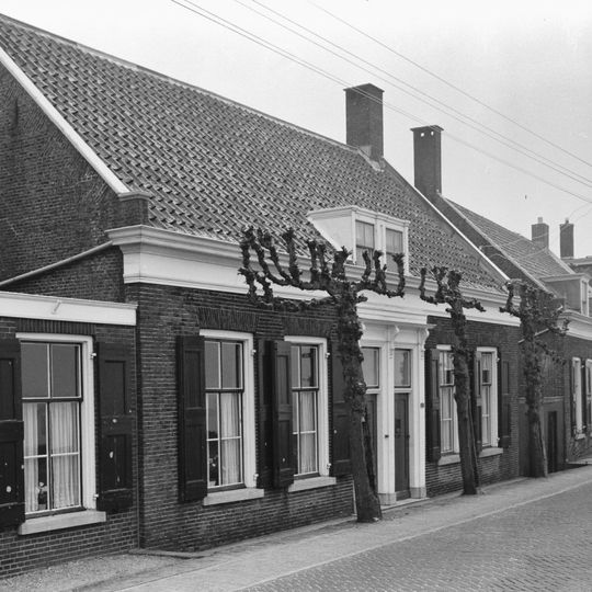 Dwarshuis van begane-grond met hoog zadeldak. Dubbele deuromlijsting met hoofdgestel op gesneden consoles. Vensters, die bij nr 283 nog hun zesruitsramen hebben bewaard, voorzien van luiken