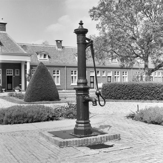 Centraal in de binnenhof van het woningcomplex gelegen gietijzeren waterpomp