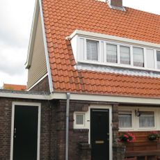 Blok met 8 keukenwoningen, zo genoemd vanwege destijds nieuwe plaatsing van keuken aan de voorzijde, aan de zijkant een houten topgevel, bouwstijl Amsterdamse School.