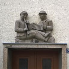 Vier Reliefplatten über den Hauseingängen einer Wohnhauszeile, Gebäude selbst keine Denkmale An der weißen Mauer 22, 24, 26, 28