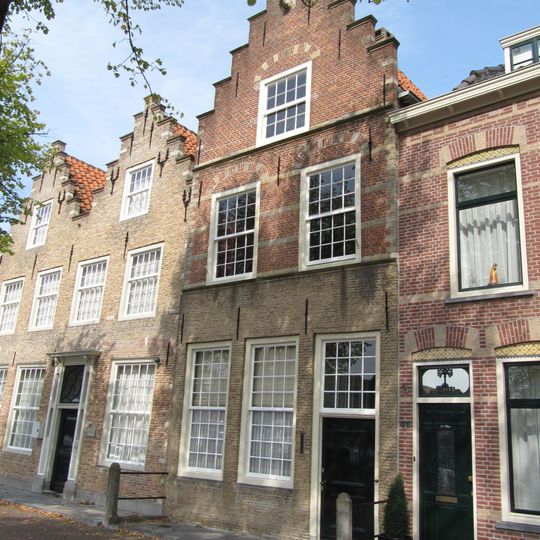 Gepleisterde lijstgevel voor huis van parterre en verdieping met schilddak. Stoep met stoeppalen