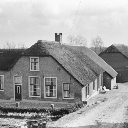 Boerderij met puntgevel en links uitgebouwde opkamer. Vensters met goede roedenverdeling in de ramen. Houten schuur achter de boerderij
