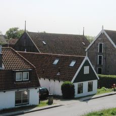 Pand opgetrokken zonder verdieping onder langgerekt pannen zadeldak tussen puntgevels met houten top