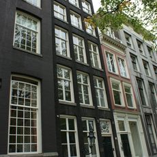 Pand met gevel onder rijk gesneden rechte lijst met deurpartij uit dezelfde tijd en vier stoeppalen