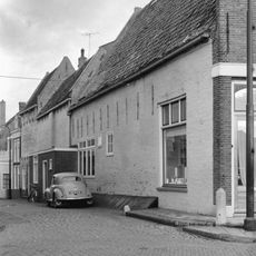 Diep pand met twee achterhuizen en brede halsgevel met aanzetkrullen en gezwenkte bekroning