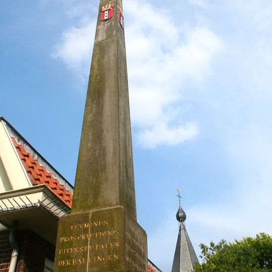Banpaal in de vorm van een natuurstenen obelisk op bakstenen voet