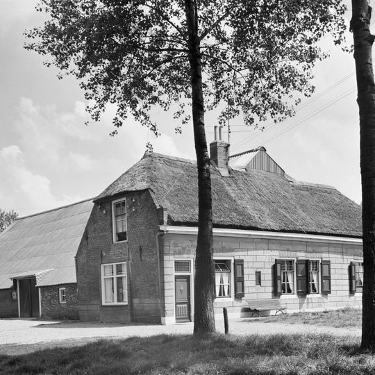 Boerderij. Dwars woonhuis onder rieten wolfdak en met gepleisterde voorgevel onder houten lijst. In de zijgevels sierankers en in de rechterzijgevel een half kruiskozijn.