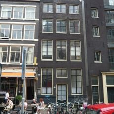 Pand met gevel onder gebeeldhouwde verhoogde lijst met vazen en borstbeeld