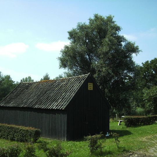 Vrijstaand, houten dijkmagazijn aan de zuidzijde van de dijk