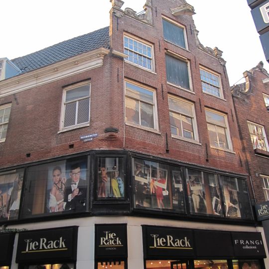 Hoekhuis met halsgevel met gedeelde vleugelstukken en hoekvazen. In de incomplete afdekking